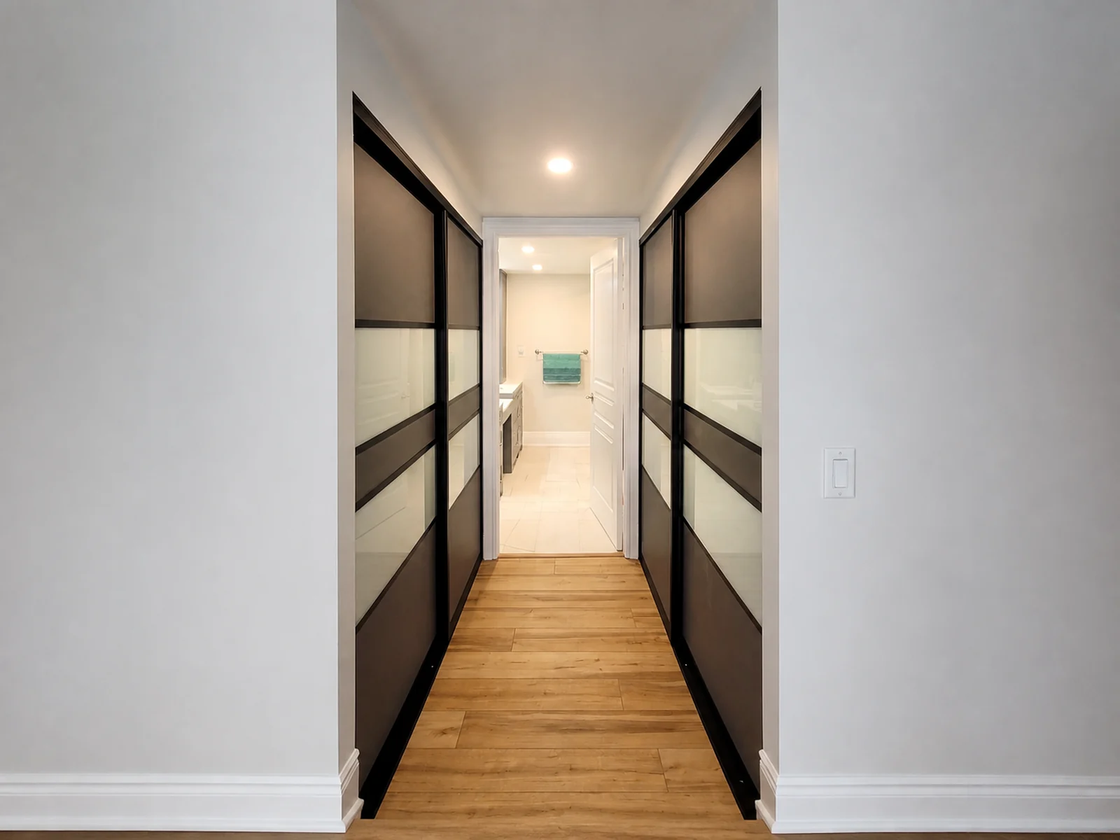 Completed sliding closet doors installed along both sides of a bedroom-to-washroom passage.