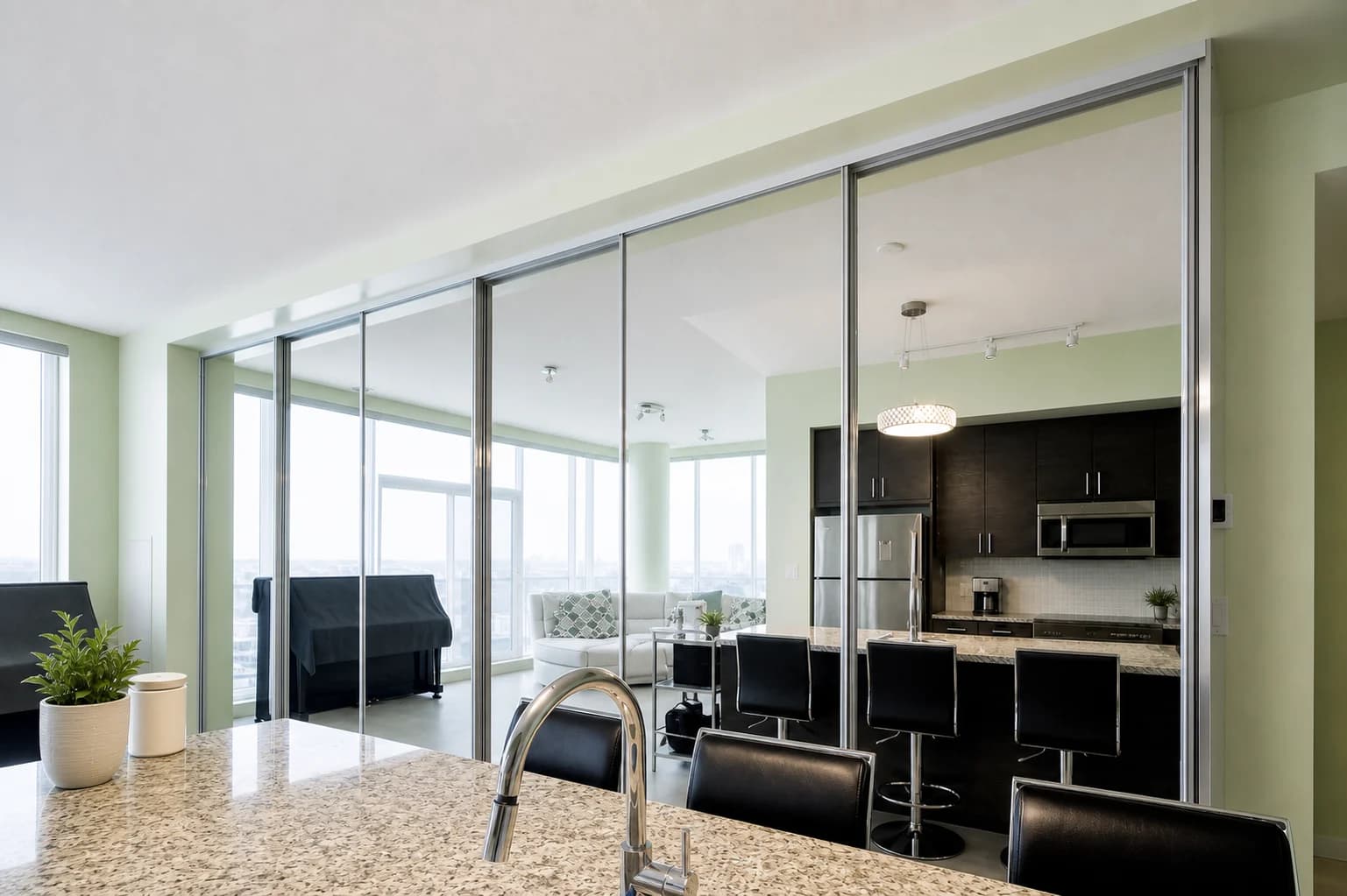 Completed sliding glass room divider separating a kitchen and living area while preserving light.