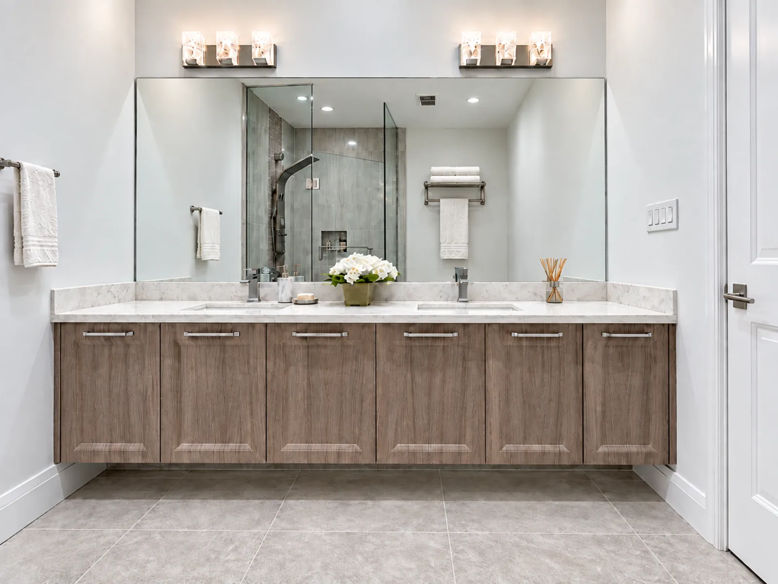 Completed Roomidea bathroom with a floating wood-toned double vanity, paired sinks, door and drawer storage and a wall-wide mirror