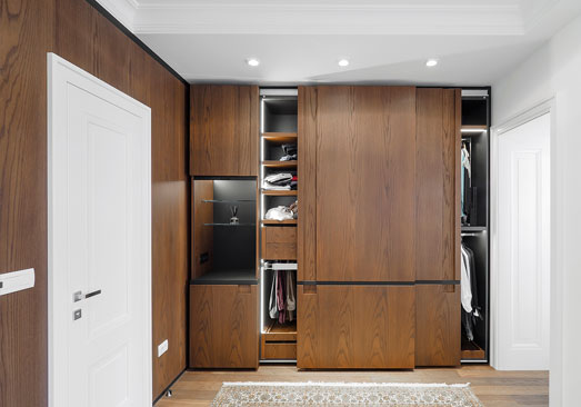 Completed Roomidea full-height wood cabinetry with integrated storage and illuminated open sections