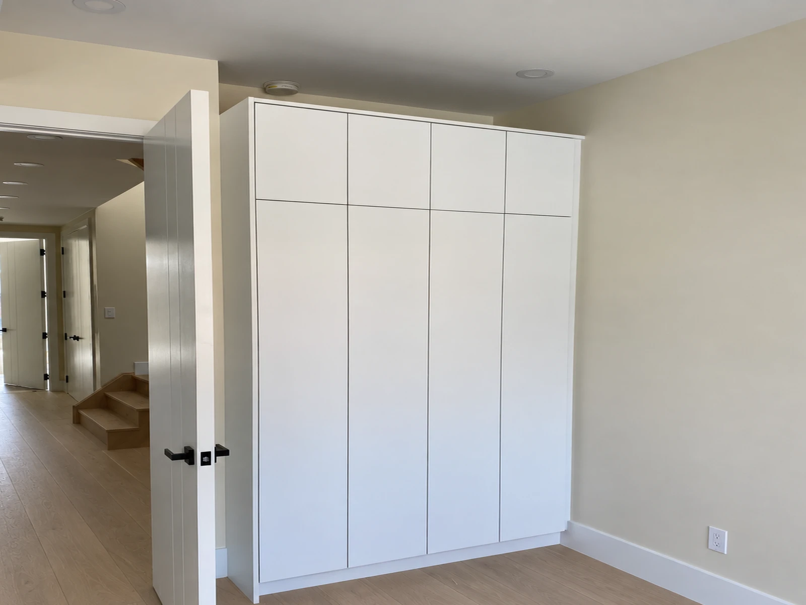 Push-to-open freestanding wardrobe fitted into a shallow bedroom niche