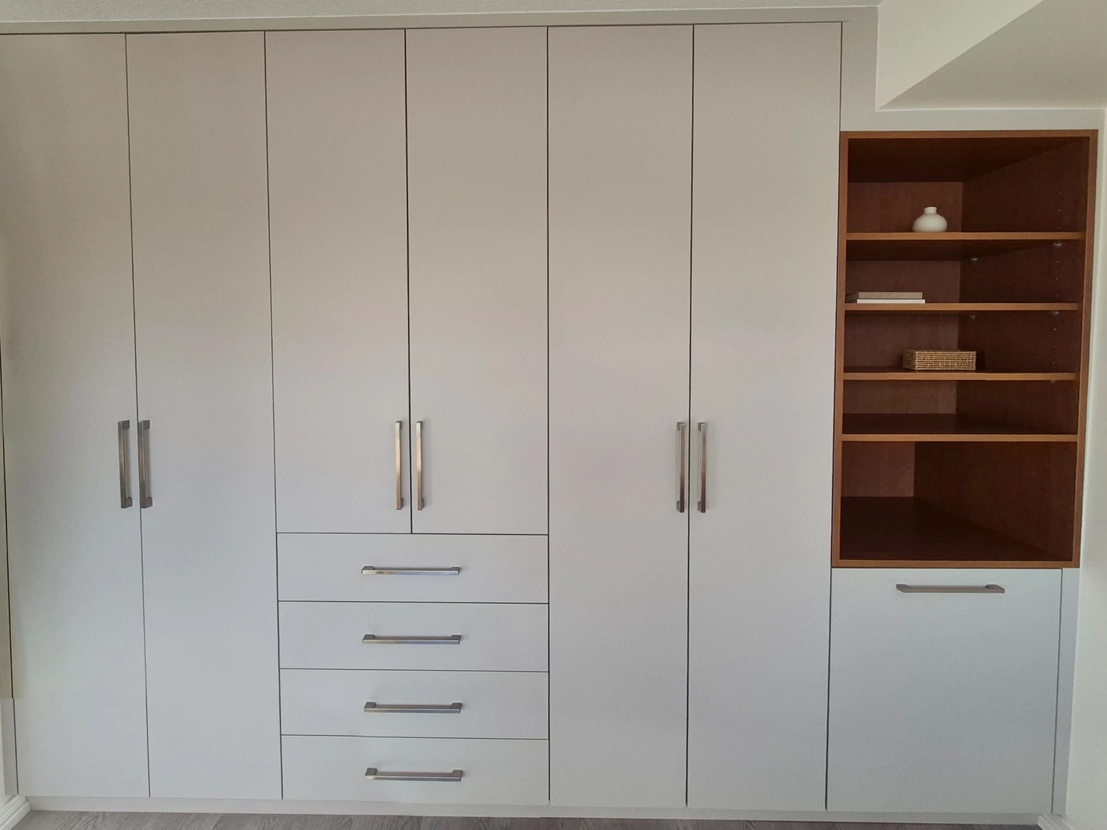 Built-in wardrobe with open shelving designed beneath an existing bulkhead