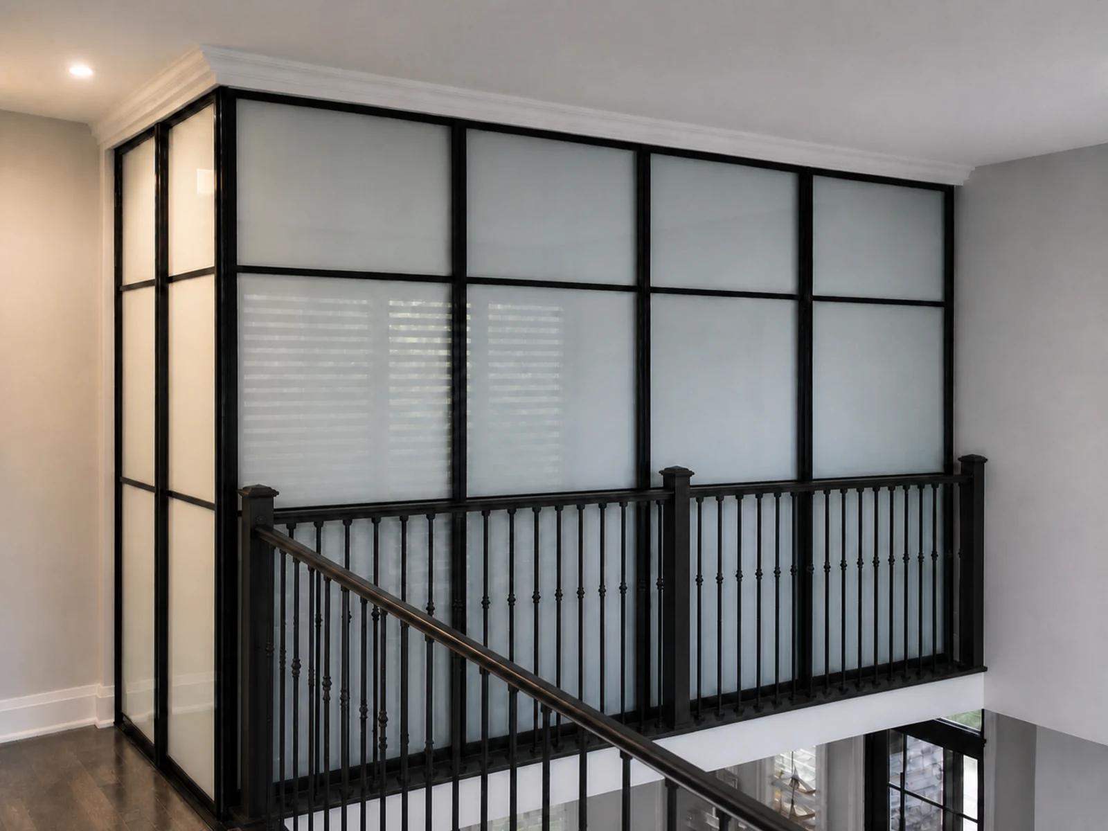 Black-framed frosted-glass room divider installed beside an open stair landing for added privacy.