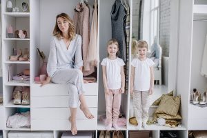 Female Wardrobe. Stylish Mother, Cute Twin Daughters Wearing Com Female wardrobe. Stylish mother, cute twin daughters wearing comfortable home clothes posing in closet. Happy motherhood